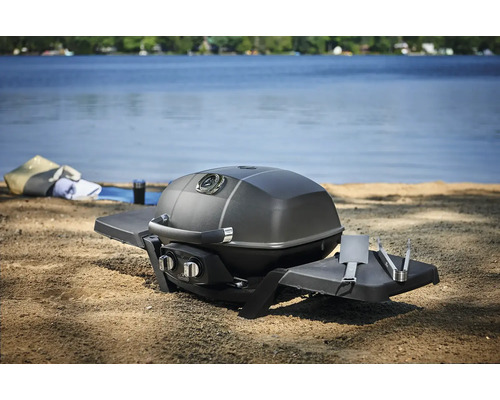 Bärbar gasolgrill med grillverktyg vid sjöstranden