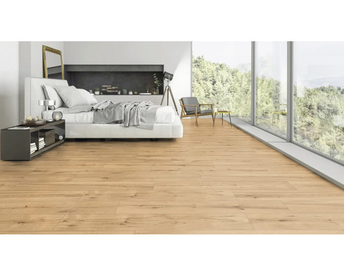 Ljust sovrum med trägolv, säng och stort fönster med utsikt över naturen.