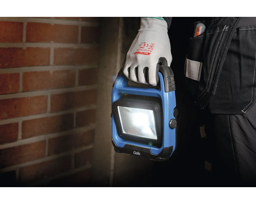 En person med handskar håller en blå Gella arbetslampa.