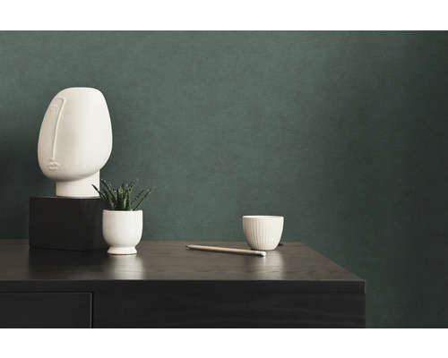 Dekorativ scen med konstnärligt huvud, växt, mugg och penna på en byrå.