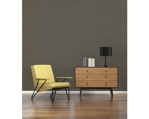 Vardagsrum med fåtölj, byrå, lampa och böcker