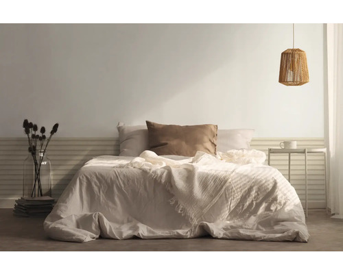 Sovrum med säng, kuddar, överkast, sängbord och lampa