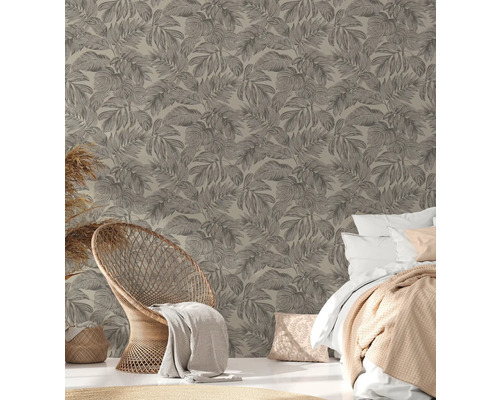 Ett sovrum med en vägg med bladmönster, en rottingfåtölj och en säng.