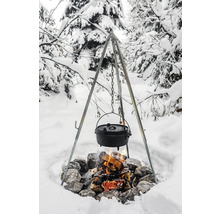 Trefot över lägereld med gjutjärnsgryta i ett snöigt landskap