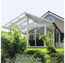 En glas- och metallvinterträdgård med ett transparent tak vid ett hus.