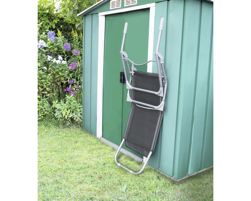 Fällbar solstol av metall och textil står lutad mot ett grönt trädgårdsskjul.