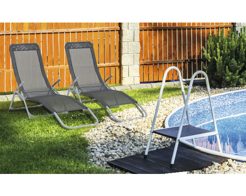 Två solstolar bredvid en pool med en stege