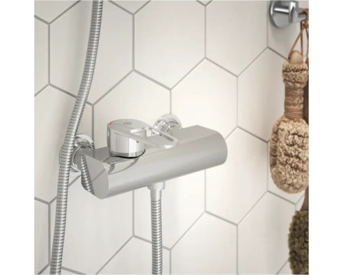 Duschblandare med utanpåliggande rör och duschslang framför hexagonala plattor