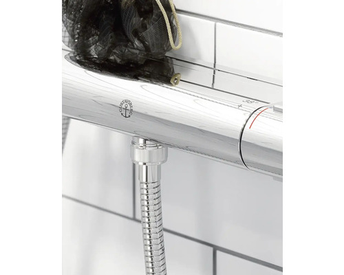 Detaljvy av en duschblandare med termostat och duschslang, inklusive förvaringshylla och Gustavsberg-logotypen.