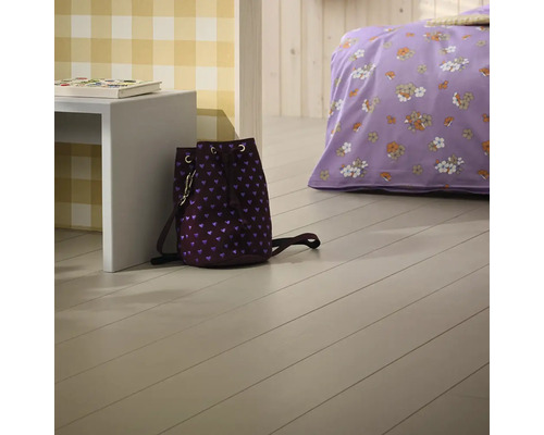 Utsikt över ett rum med trägolv, säng och ryggsäck