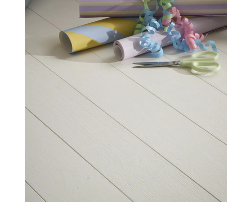 Olika presentpappersrullar, presentband och en sax på ett trägolv