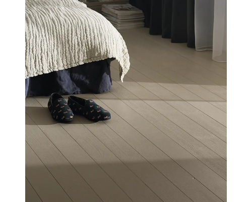 Sovrumsmiljö med säng och tofflor på trägolv