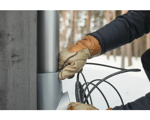 En person installerar en kabel på en mast