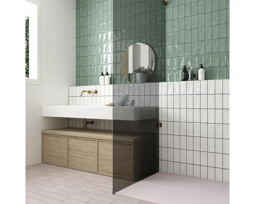 Badrum med gröna och vita väggplattor, handfat och underskåp i trä