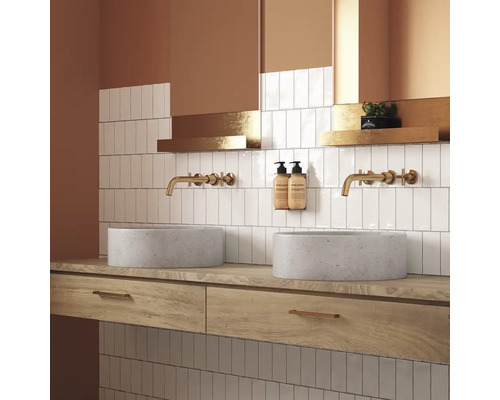 Badrum med två runda handfat, kranar, hyllor och vita kakelplattor