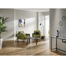 Ljust vardagsrum med trägolv, två gröna fåtöljer, soffbord och modern dekoration