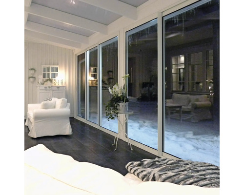 Ljust uterum med skjutdörrar, vita möbler och utsikt över den snötäckta trädgården.