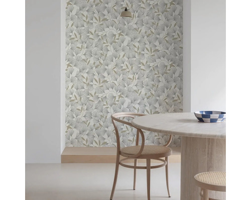 Rumsscen med mönstrad tapet med löv, ett runt bord och en trästol