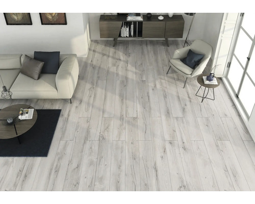 Ljust vardagsrum med trägolv, soffa, fåtölj och skänk