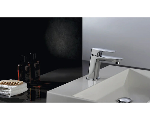 Tvättställsblandare på ett tvättställ med handduk och kosmetiska produkter