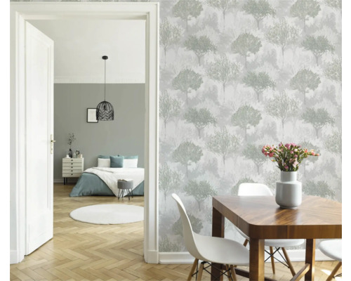 Matsal med träbord, vita stolar och tapeter med trädmotiv.