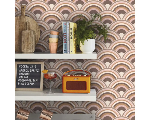 Hyllor med skärbrädor, porslin, växter, böcker, cocktailglas, radio, cocktailmeny och tapet med bågmönster