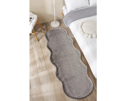 Interiörbild av ett sovrum med en säng och en grå matta i pälsdesign.
