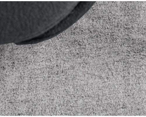 Närbild av en matta med en del av en sittmöbel.