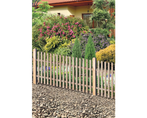 Trädgårdsstaket av trä framför en blommande trädgård