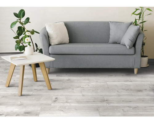 Ljust vardagsrum med soffa, bord och träklinkergolv.