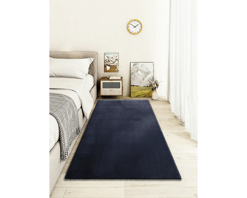 Interiörbild av ett sovrum med en säng och en rektangulär matta.