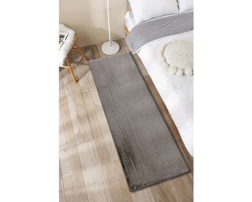 Grå matta bredvid en säng på ett trägolv