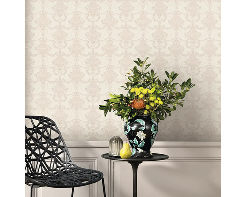 Dekorativ vägg med blommönstrad tapet, kompletterad med ett bord med blomvas och frukt.