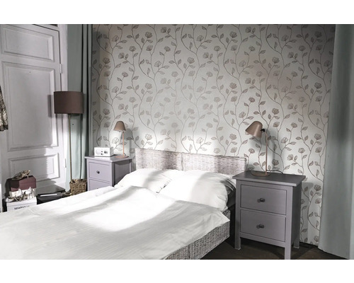 Sovrum med säng, sängbord och blommig tapet