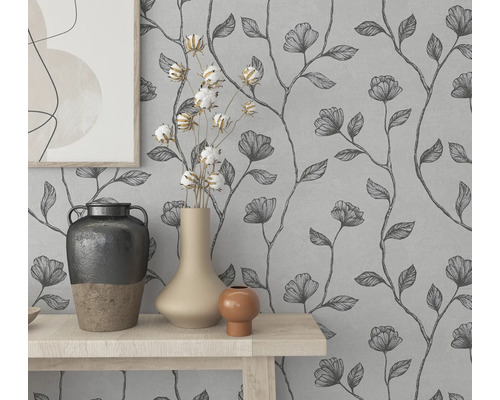 Väggdekoration med blommig tapet och dekorativa vaser på ett bord.