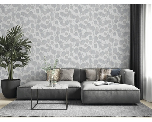 Vardagsrum med grå soffa, krukväxt och tapet med bladmönster
