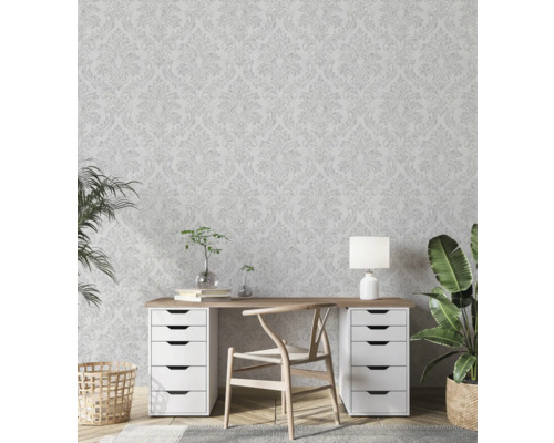 Ljust arbetsrum med blommönstrad tapet, skrivbord, stol och krukväxter