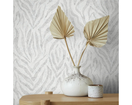 Närbild av en vägg med tapeter i zebrastil, dekorerad med en vas och torkade blad