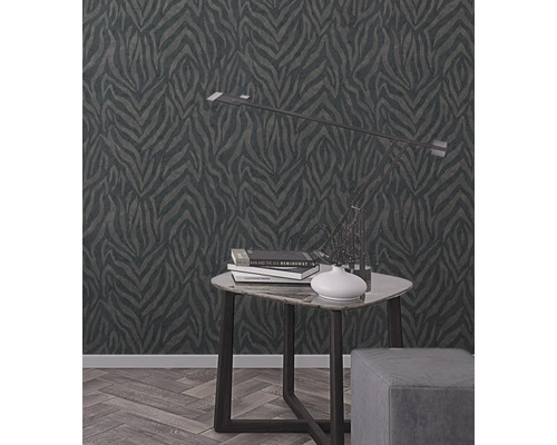 Miljöbild med en mönstrad tapet, ett bord och en lampa