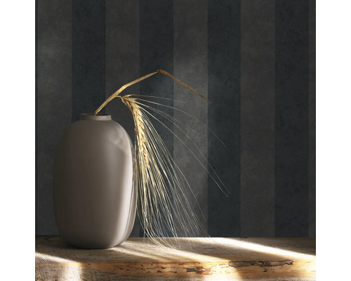 Dekorativ vas med veteax på ett träbord framför en randig tapet