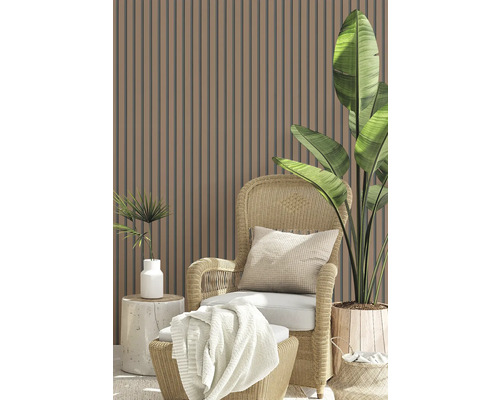 Scen med lamellvägg, rottingfåtölj, kudde, filt och blomkrukor