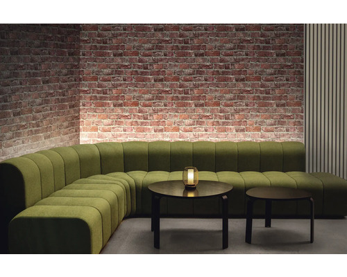 Rumsöversikt med grön modulsoffa, två runda bord och tegelvägg