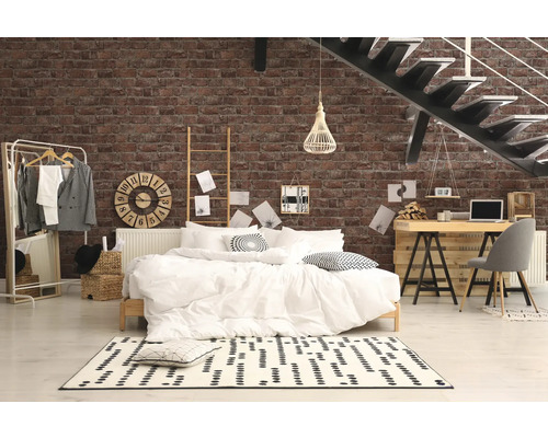 Sovrum med säng, skrivbord och trappa mot en tegelvägg