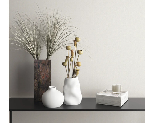 Dekorativ scen med vaser, torkade blommor, ljus och bok på en konsol