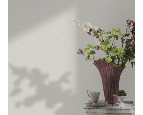 Stilleben med blommor, vas, kopp och bakverk på ett bord