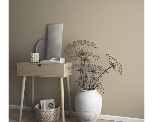 Dekorativt arrangemang med sidobord, vas med torkade blommor och dekorativa element framför en enfärgad vägg.