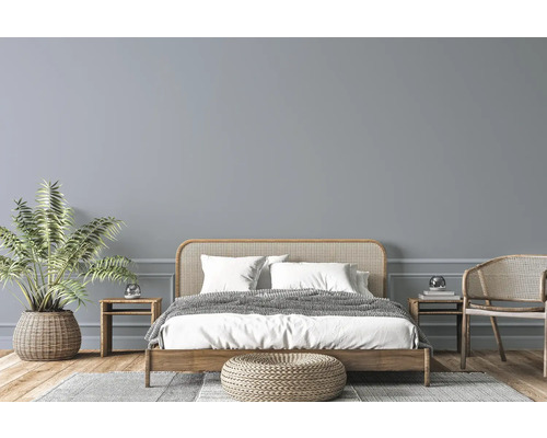 Ljust sovrum med träsäng, rottingmöbler, krukväxt och matta