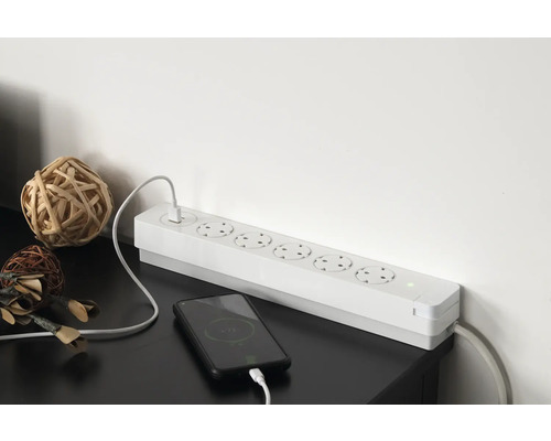 Grenuttag med sex uttag och en smarttelefon som laddas.