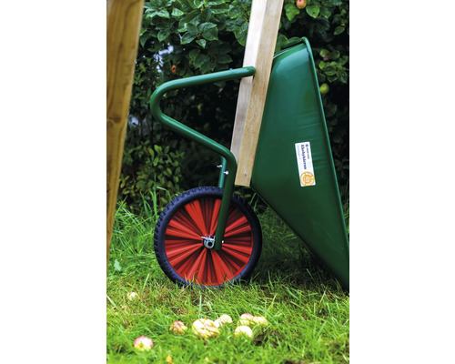 Grön skottkärra med rött hjul och träbräda i trädgården