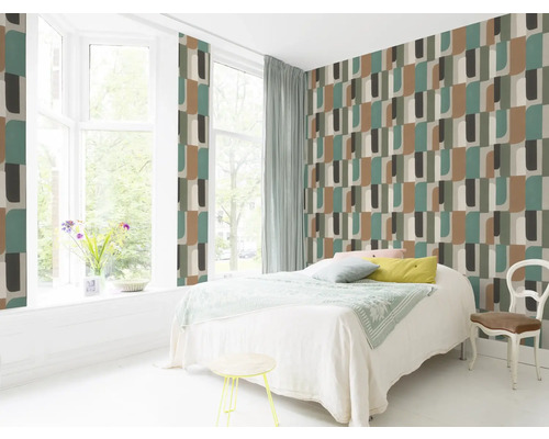 Ljust sovrum med geometrisk mönstrad tapet, säng och sittplats